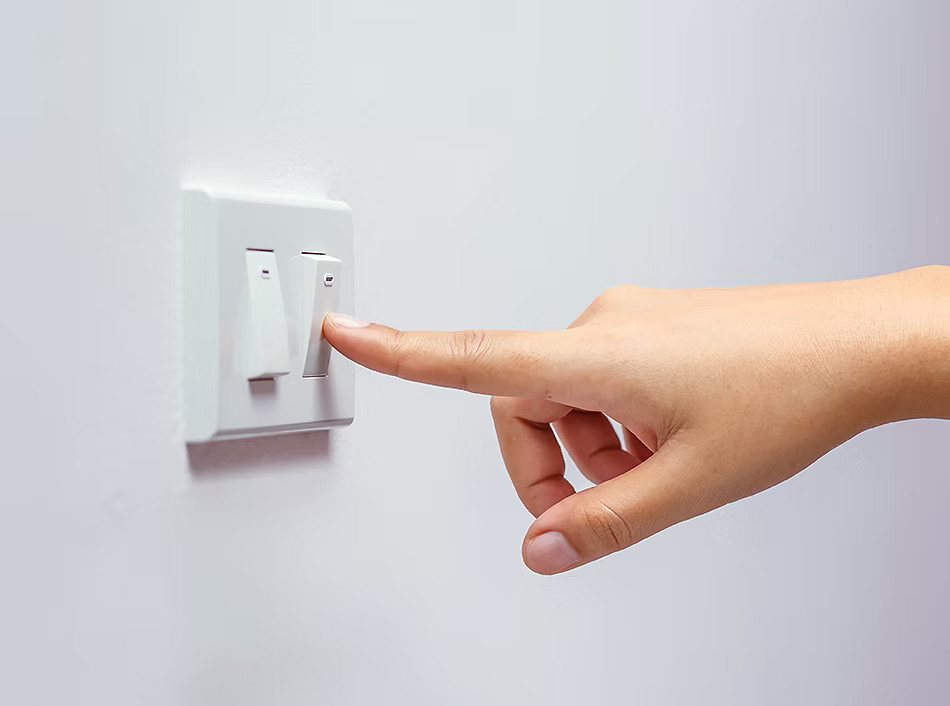 Persona presionando un interruptor de luz Troen